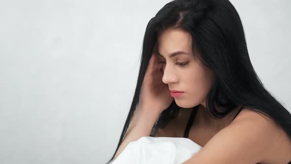 Unhappy Brunette Woman Sitting on Bed Feeling Morning Migraine