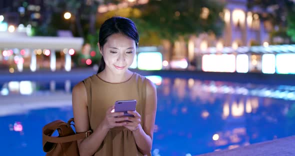 Woman use of mobile phone in the city at night