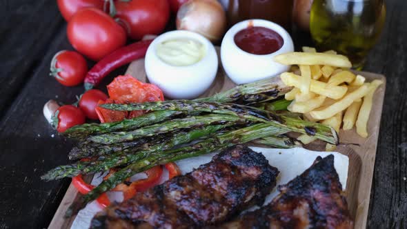 Delicious Beef or Pork Grilled Ribs Served with Aspargus and French Fries on a Wooden Board