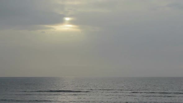 Sun Hiding Behind Gray Clouds in Gloomy Sky Over Endless Sea Surface