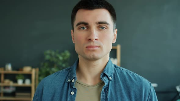 Slow Motion Portrait of Serious Young Man Looking at Camera Standing Alone at Home a