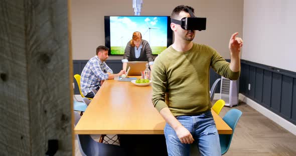 Executive using virtual reality headset while colleagues working in background 