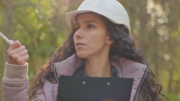 Female Technician Walking Taking Notes on Clipboard Notepad Paper in Park During Logging