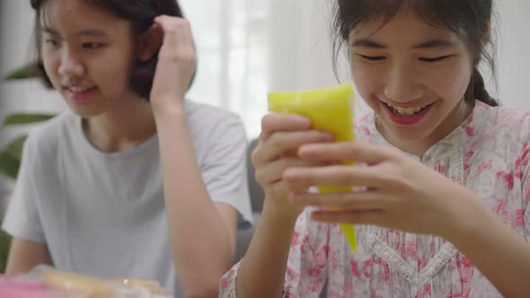 Cute Asian girl drawing on biscuit cookie for make delicious dessert, Home school cooking class.