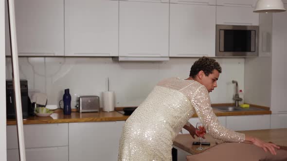 A Man in a Dress Standing in Front the Mirror Doing Makeup