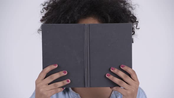 Face of Young African Woman with Eyeglasses Covering Face with Book