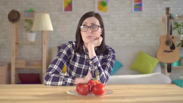 Young Woman Looks at Tomatoes Which Cause an Allergic Reaction