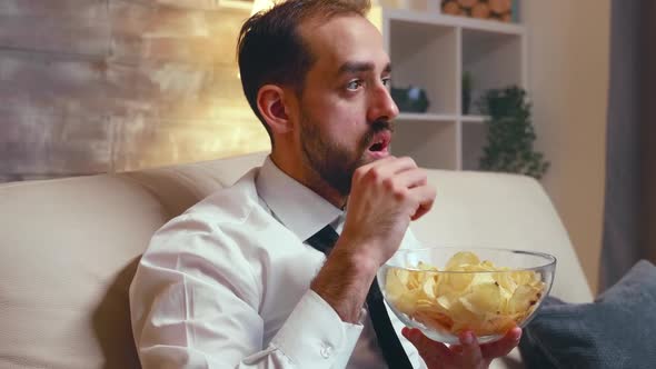 Businessman in Formal Wear Eating Chips From a Bowl