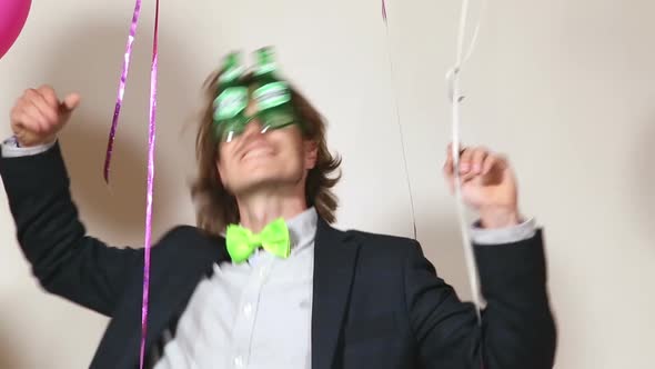 Funny man dancing wearing beer sunglasses and holding balloons in photo booth