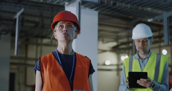 Mature Engineer Speaking with Assistant Making Notes on Tablet