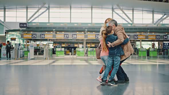 Happy Father Meeting His Arriving Family From Vacation Travel Embracing with Wife and Children at