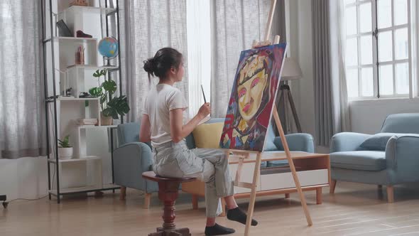 Asian Artist Girl Holding Paintbrush And Thinking Before Painting A Girl's Hair On The Canvas