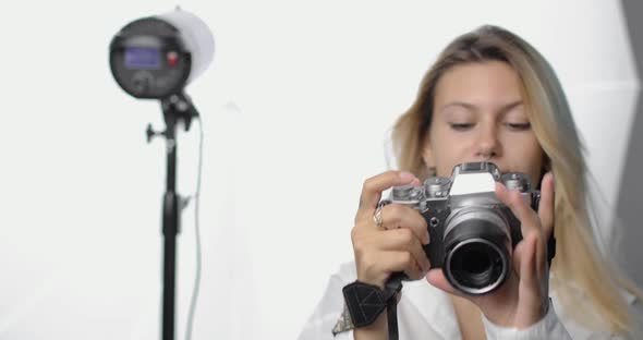 Portrait of a Stylish Young Woman Photographer in a White Shirt with a Pierced Nose and Long Blond