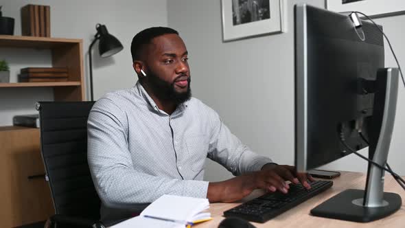 Focused AfricanAmerican Guy Using PC for Work