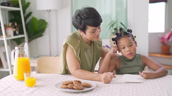 4K Mother helping little daughter do homework and eating cookie together