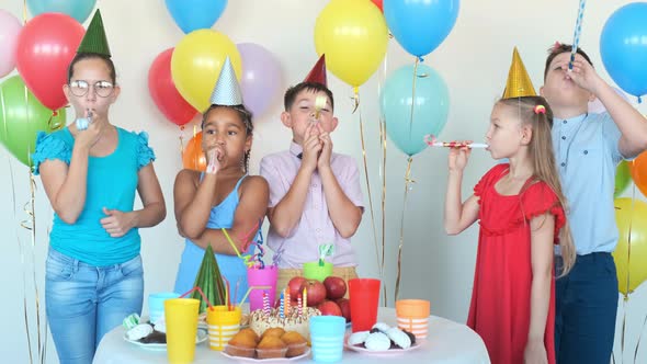 Children Blow Party Horns Celebrating Birthday at Table