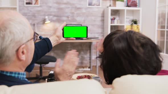 Back View of Elderly Age Couple Looking at Phone with Green Screen
