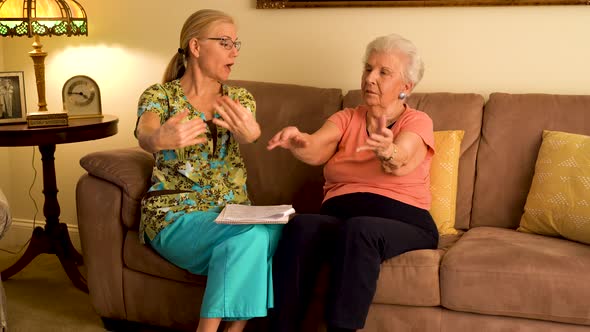 Home healthcare nurse helping elderly woman with hand and wrist range of motion stretches.