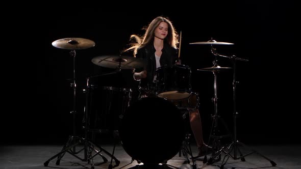 Drummer Girl Starts Playing Energetic Music, She Smiles. Black Background
