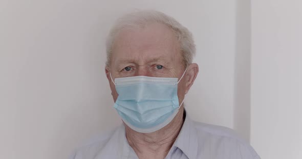 Portrait of Sad Elderly Man in Mask Looking at Camera Indoor During Pandemic