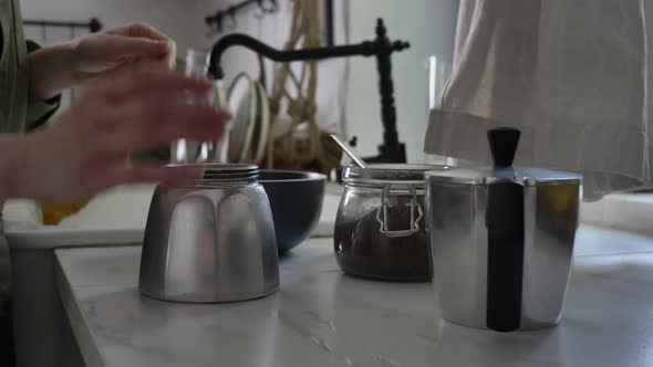 Woman make a coffee in moka pot in kitchen