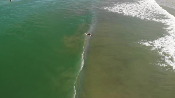 Aerial shot of surfer catching a wave then wiping out.