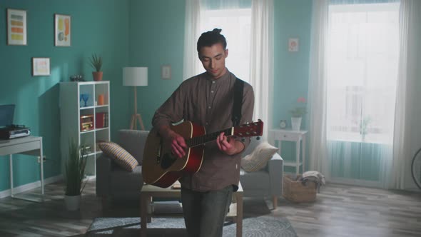 Young Man Is Playing Guitar at Home