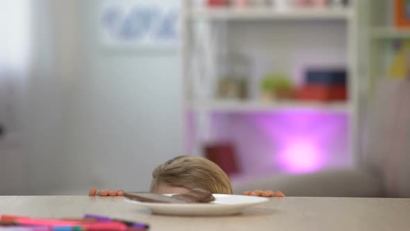 Schoolboy Taking Secretly Chocolate From White Plate on Table, Sweet Dessert