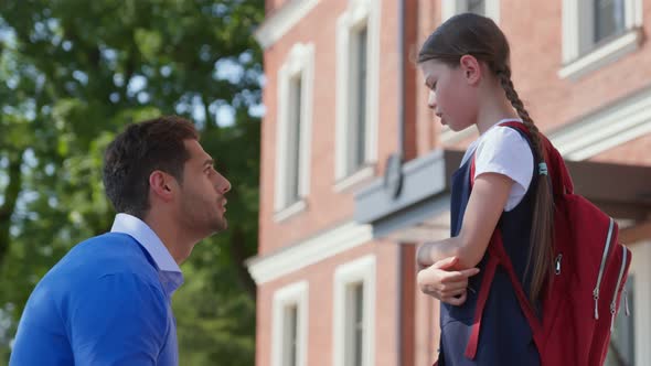 Side View of Father Cheering Upset Daughter Outside School Building