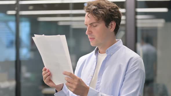 Portrait of Man Reacting to Loss While Reading Documents