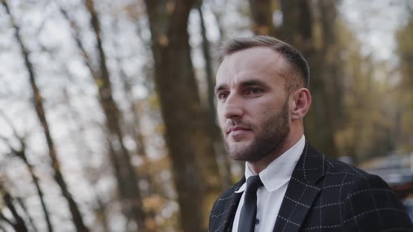 Portrait of Happy Confident Man Looks Straight in Autumn Park