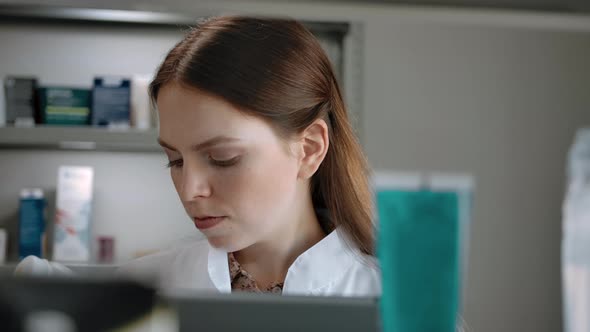Female Pharmacist Checks Medical Products with List in Tablet