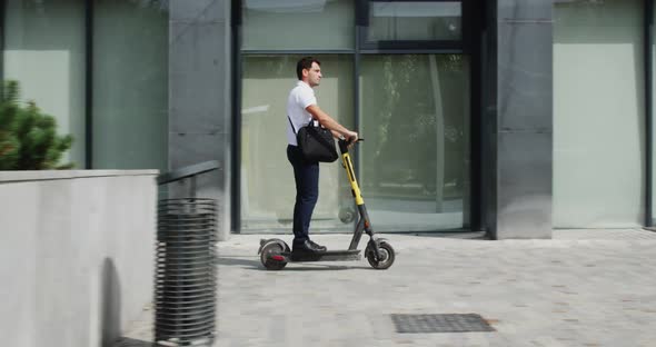 Male Businessman with Briefcase Riding on Escooter in Modern Summer Downtown