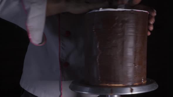 cook decorating chocolate cake with fondant