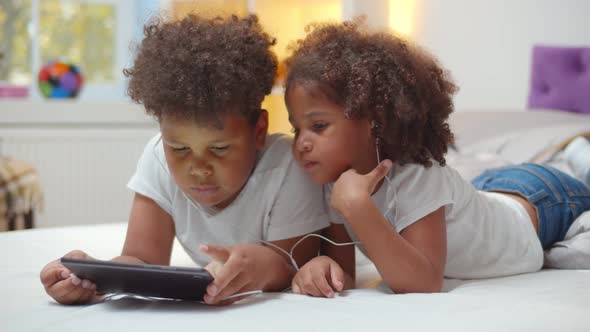Portrait of Adorable African Boy and Girl Kids Watching Cartoon in Earphones on Digital Tablet