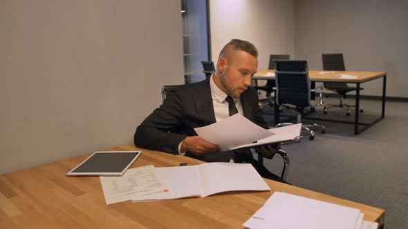 Confident Businessman Working with Documents in Night Office Indoor