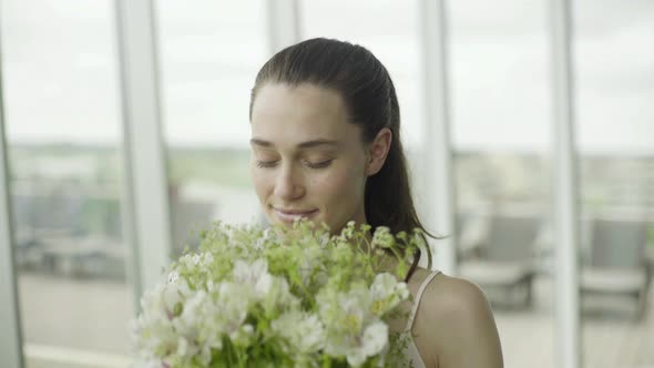 Young woman smelling bouquet of fresh flowers