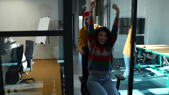 Joyful Mixed Race Woman Riding Chair in Corridor