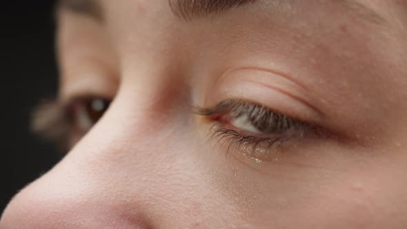 Closeup of Crying Brown Eyes Watery Eye of Young Woman Shooting of Tears Rolling Down the Cheeks