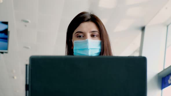 Portrait of Woman in Protective Mask, Working on Laptop in a Public Place. Social Responsibility