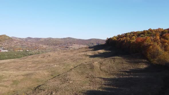 Aerial view of country hills at sunset in autumn season. Beautiful rural scene with dead nature, ear