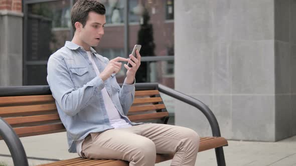 Outdoor Young Man Upset by Loss while Using Smartphone