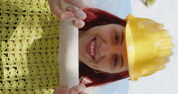 Portrait of an engineer girl smiling behind the rolled up project