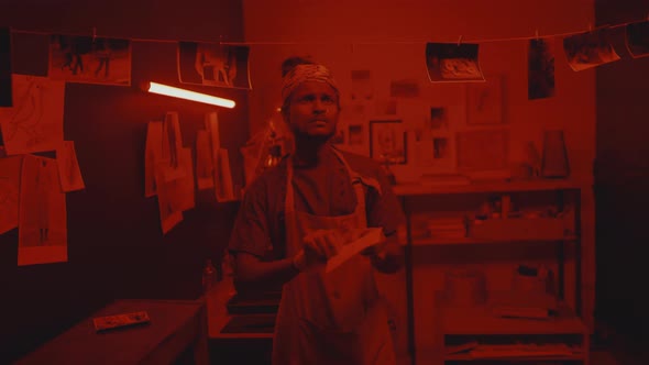 Photographer Hanging Printed Photos on Rope in Darkroom