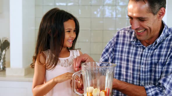 Father and daughter preparing smoothie in kitchen