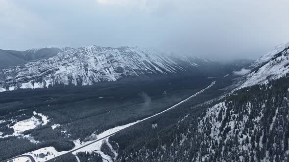 Drone filming the black valley on slopes of snowy winter mountains in Kananaskis, Alberta, Canada