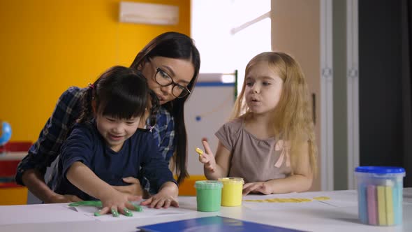 Diverse Kids with Teacher Hand Painting in Class