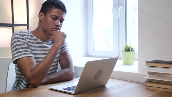 Black Man Thinking and Working on Laptop