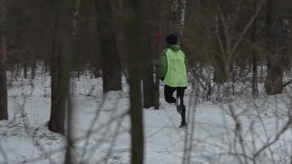 Man Running Through Forest in Wnter Cross-Country Training