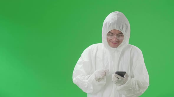 Man Wear Protective Uniform Ppe And Use Mobile Phone With Pointing To Side In Green Screen Studio